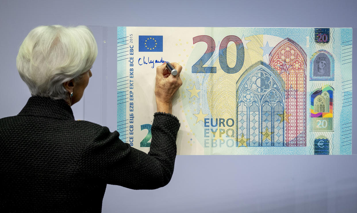 The new President of the European Central Bank Christine Lagarde adds her signature to an oversize euro banknote at the ECB in Frankfurt, Germany, Wednesday, Nov. 27, 2019. (AP Photo/Michael Probst)