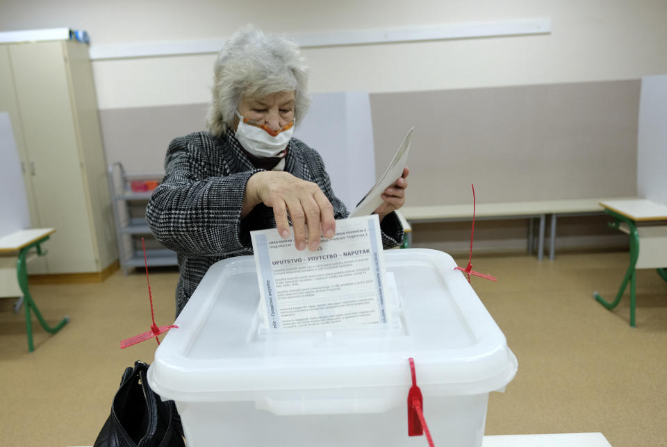 A woman casts her ballot for the local elections at a polling station in Mostar, Bosnia, Sunday, Dec. 20, 2020. Divided between Muslim Bosniaks and Catholic Croats, who fought fiercely for control over the city during the 1990s conflict, Mostar has not held a local poll since 2008, when Bosnia's constitutional court declared its election rules to be discriminatory and ordered that they be changed. (AP Photo/Kemal Softic)