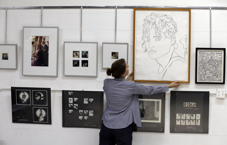 Mary Dowd of Myers Fine Art auction house adjusts an Andy Warhol drawing of Martin Burgoyne Tuesday, Jan. 21, 2014 in St. Petersburg, Fla. Burgoyne was a British-born artist, who was Madonna’s roommate in Manhattan and a key figure in her career before she became famous. He died of AIDS in 1986. His parents are auctioning off a collection that is like a 1980's time capsule. It includes art from Andy Warhol and Keith Haring and pencil drawings for the cover of Madonna's "Burning Up” album, along with several photos of a young Madonna before she became famous. The auction will take place Feb. 9, 2014. (AP Photo/Chris O'Meara)