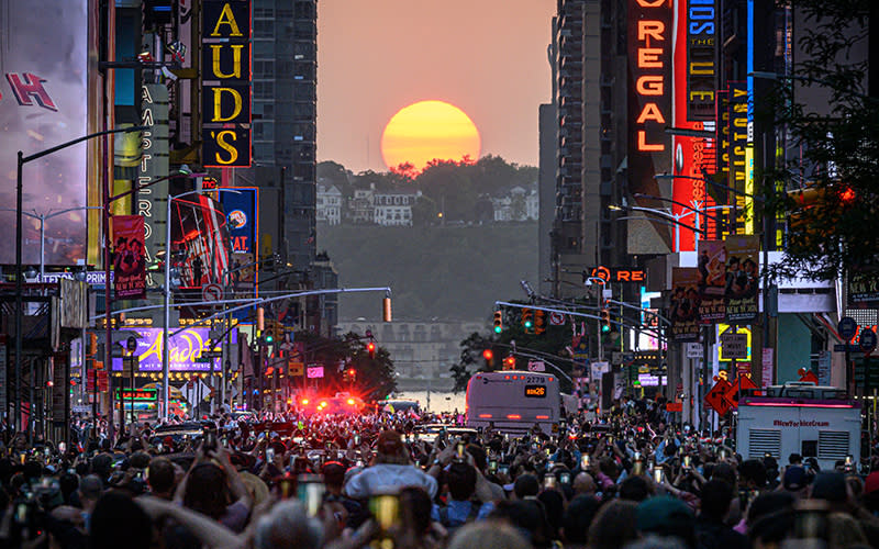 The sun sets in alignment with Manhattan streets running east and west