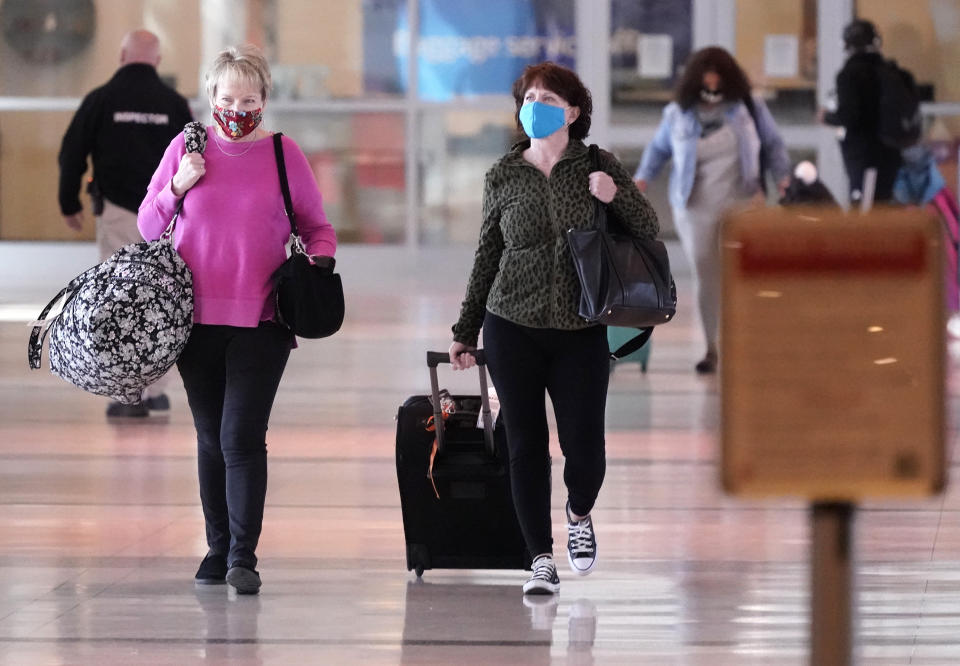 Dos mujeres con mascarillas caminan por un pasillo del aeropuerto Love Field de Dallas, el martes 2 de marzo de 2021. (AP Foto/LM Otero)