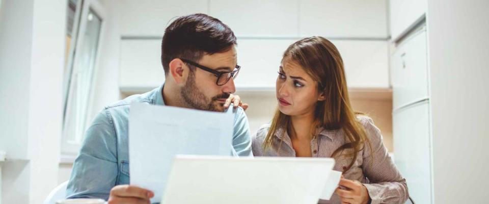 Shot of a young couple looking stressed while going over their finances at home. Shot of a young couple looking anxious while doing their budget at home.