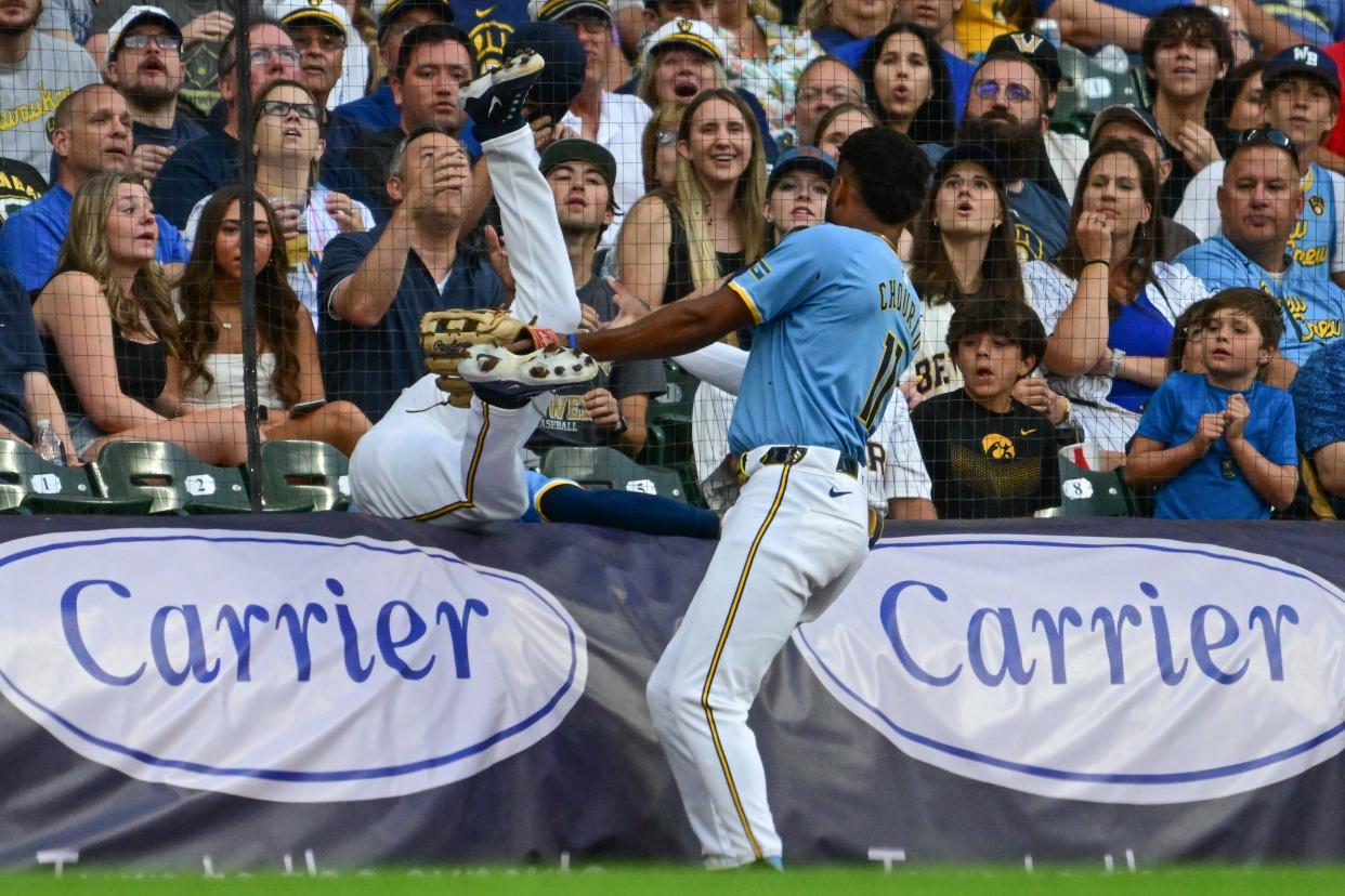 Brewers third baseman Joey Ortiz tumbles over the rolled-up tarp chasing a foul pop up against the Marlins as leftfielder Jackson Chourio comes to his aid during the second inning Friday night at American Family Field.