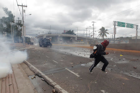 A supporter of Salvador Nasralla, presidential candidate for the Opposition Alliance Against the Dictatorship, runs away from police during a protest while awaiting official presidential election results in Tegucigalpa, Honduras November 30, 2017. REUTERS/Jorge Cabrera