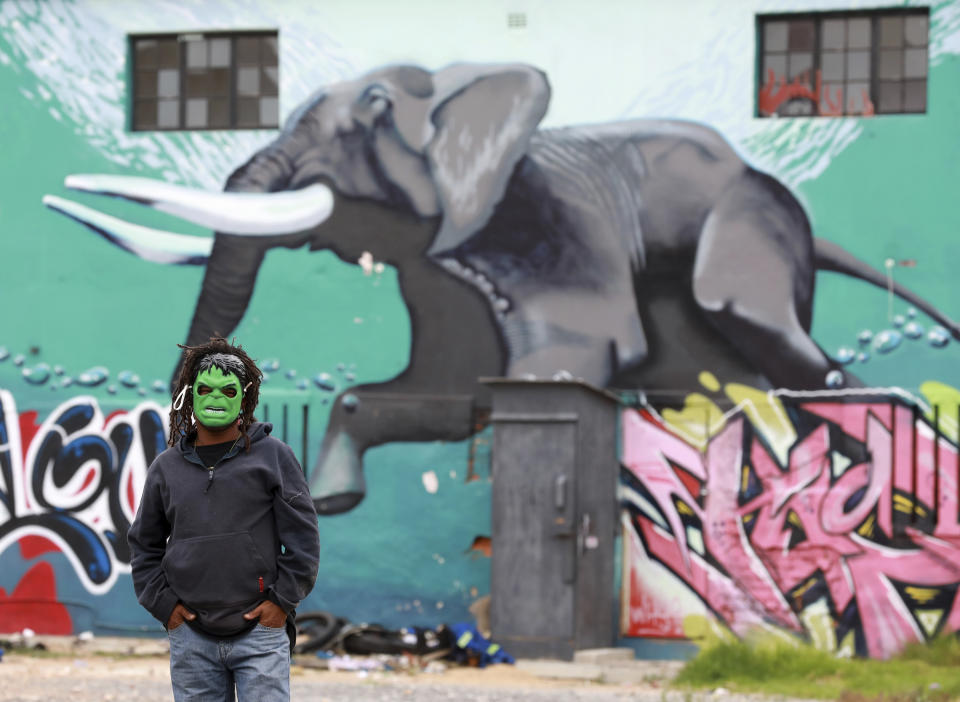 A man wearing a mask against a wall of graffiti in Woodstock, a suburb of Cape Town, South Africa, Thursday, May 21, 2020. With dramatically increased community transmissions, Cape Town has become the centre of the coronavirus outbreak in South Africa and the entire continent. (AP Photo/Nardus Engelbrecht)