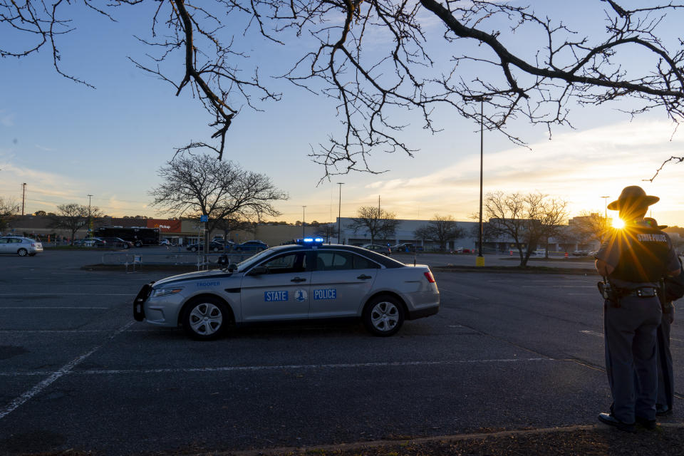 The sun rises behind two Virginia State Troopers as law enforcement works the scene of a mass shooting at a Walmart, Wednesday, Nov. 23, 2022, in Chesapeake, Va. The store was busy just before the shooting Tuesday night with people stocking up ahead of the Thanksgiving holiday. (AP Photo/Alex Brandon)