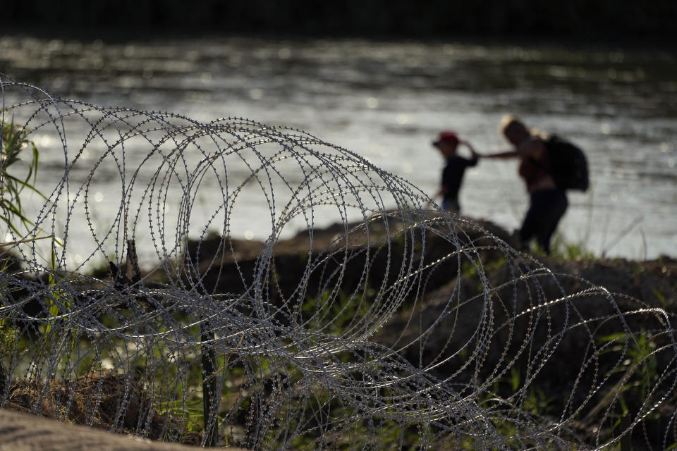 Migrants walk along concertina wire as they try to cross the Rio Grande at the Texas-U.S. border in Eagle Pass, Texas, Thursday, July 6, 2023. (AP Photo/Eric Gay)