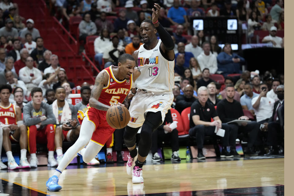 Atlanta Hawks guard Dejounte Murray (5) drives past Miami Heat center Bam Adebayo (13) during the first half of an NBA basketball game, Monday, March 6, 2023, in Miami. (AP Photo/Wilfredo Lee)