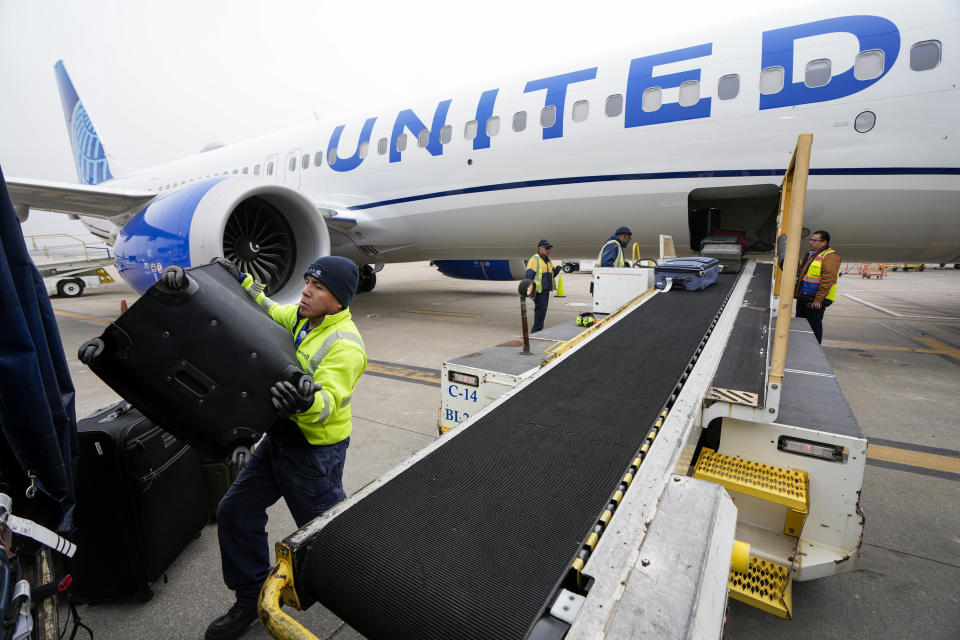 FILE - Juan Chavez handles baggage as is comes off a United Airlines aircraft upon landing at George Bush Intercontinental Airport on Thursday, Dec. 21, 2023, in Houston. United Airlines said Friday, Feb. 23, 2024, that it is raising its fees for checking bags, following a similar move earlier this week by American Airlines. (Brett Coomer/Houston Chronicle via AP, File)