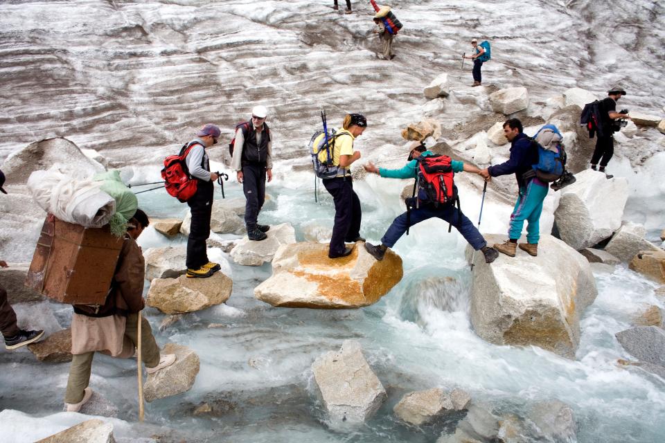 Aided by mountain guides, trekkers cross a stream on the Baltoro Glacier.