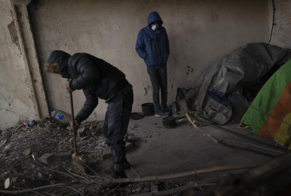 Migrants clean an abandoned hangar while bracing against harsh winter weather near the Hungarian border, outside of the village of Majdan, Serbia, Tuesday, Jan. 11, 2022. Hungary's nationalist prime minister, Viktor Orban, is keen to use the threat of migrants at his country's southern border to give him an advantage in upcoming elections. But the scale of migration pressure claimed by Orban is drawn into question by statistics from neighboring Serbia and the European Union's border agency. (AP Photo/Bela Szandelszky)