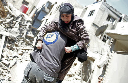 A rescue worker holds an injured girl in the rebel held besieged town of Hamouriyeh, eastern Ghouta, near Damascus, Syria February 21, 2018. REUTERS/Bassam Khabieh