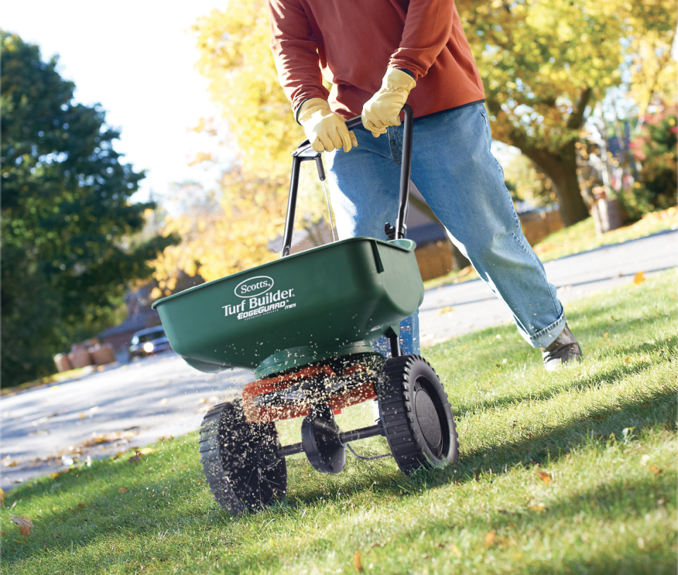 Person using a spreader to fertilize their lawn