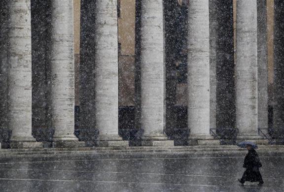 A priest walks as it snows in Saint Peter's Square at the Vatican February 12, 2010.