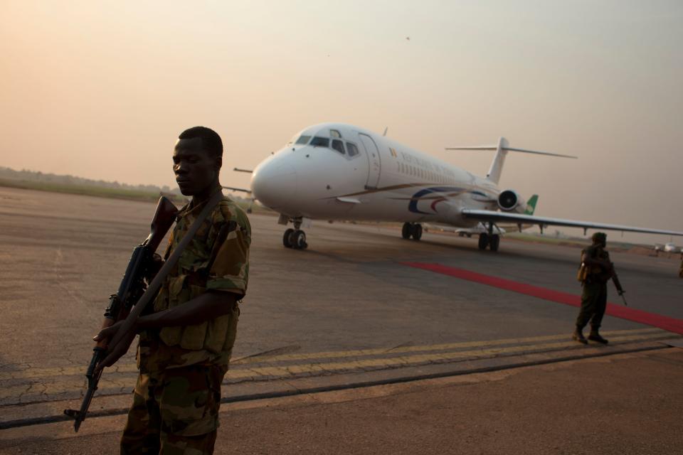 Former Seleka rebels stand guard as a Chadian plane carrying Central African Republic President Michel Djotodia departs for Ndjamena, at Mpoko Airport in Bangui, Central African Republic, Wednesday, Jan. 8, 2014. The embattled president, who has come under growing pressure to resign, traveled to neighboring Chad on Wednesday for a summit with regional leaders who want to end the bloodshed that has left more than 1,000 dead and nearly a million people displaced.(AP Photo/Rebecca Blackwell)