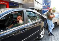 A man rests in his car as he waits for fuel at a gas station in Beirut