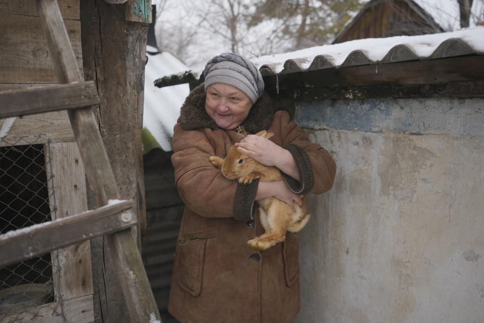 Olga, one of the 16 residents still living in a frontline village, holds a rabbit speaking to journalists at her house's yard not far from the front line in the Luhansk region, eastern Ukraine, Friday, Jan. 28, 2022. High-stakes diplomacy continued on Friday in a bid to avert a war in Eastern Europe. The urgent efforts come as 100,000 Russian troops are massed near Ukraine's border and the Biden administration worries that Russian President Vladimir Putin will mount some sort of invasion within weeks. (AP Photo/Vadim Ghirda)