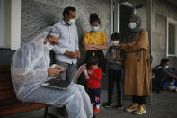 A Turkish coast guard officer at Dikili, Turkey, wearing protective gear to help prevent the spread of coronavirus, registers migrants after they were rescued in the Aegean Sea, between Turkey and Greece, Saturday, Sept. 12, 2020. Turkey is accusing Greece of large-scale pushbacks at sea — summary deportations without access to asylum procedures, in violation of international law. The Turkish coast guard says it rescued over 300 migrants "pushed back by Greek elements to Turkish waters" this month alone. Greece denies the allegations and accuses Ankara of weaponizing migrants. (AP Photo/Emrah Gurel)