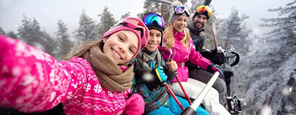 Happy family in cable car climb to ski terrain selfie