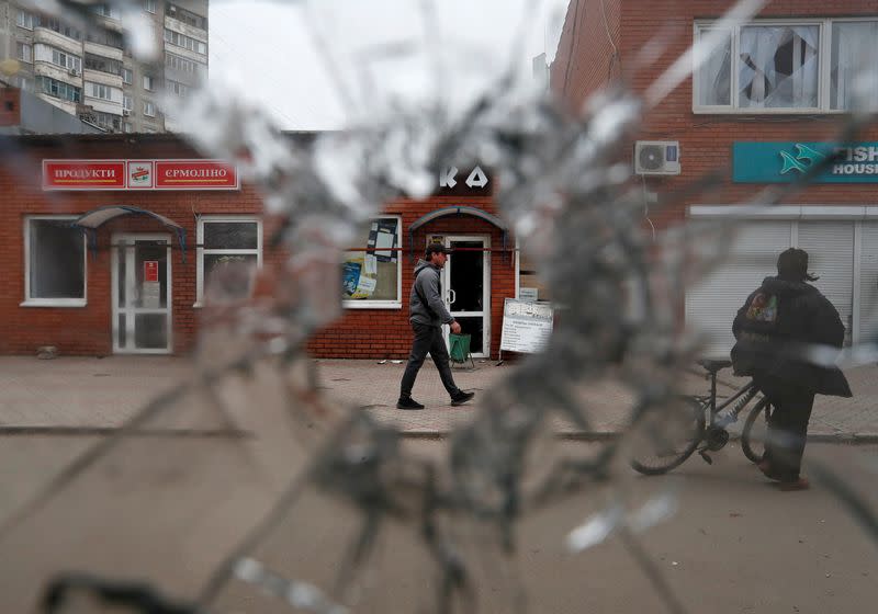 A local resident is seen through a broken window at a local market in Mariupol