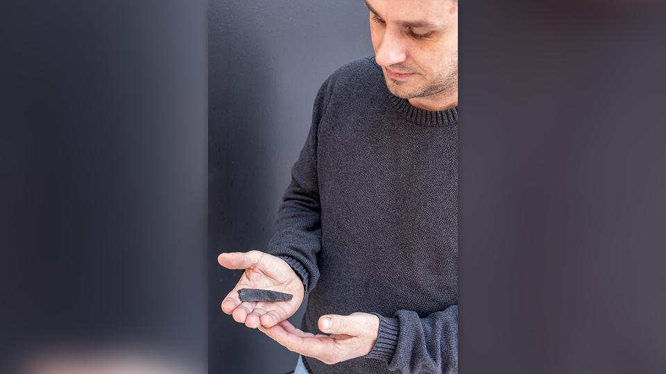 Man in gray sweater holds 1800 year-old iron knife inscribed with some of Denmark's earliest runes in his palm.