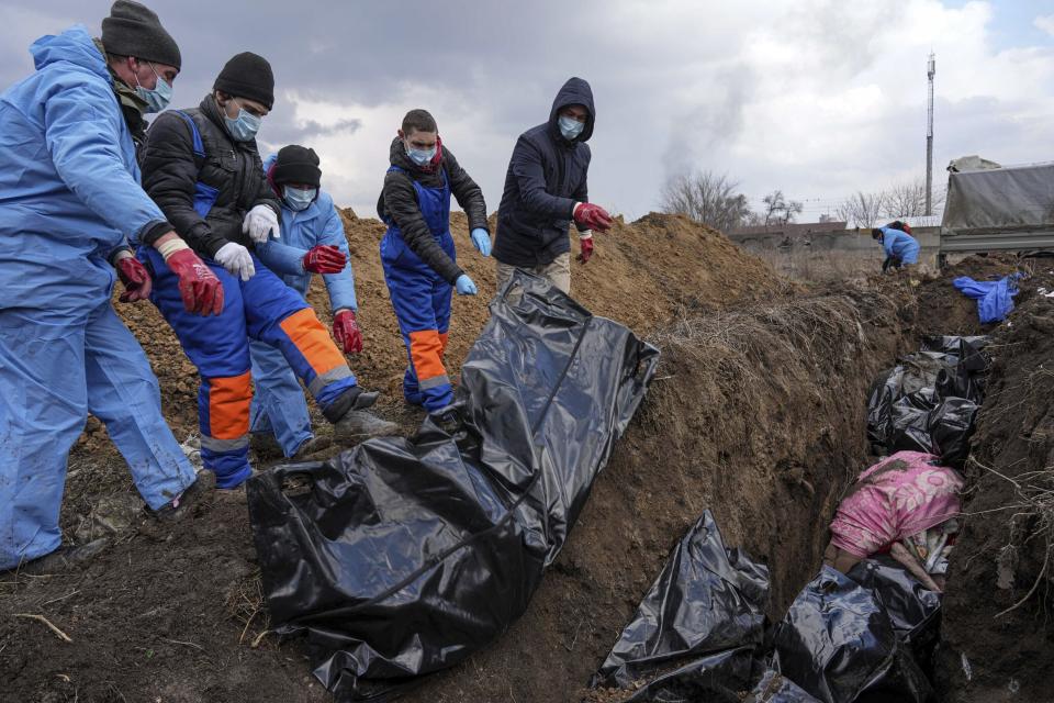 FILE - Dead bodies are placed into a mass grave on the outskirts of Mariupol, Ukraine, Wednesday, March 9, 2022 as people cannot bury their dead because of the heavy shelling by Russian forces. (AP Photo/Evgeniy Maloletka, File)