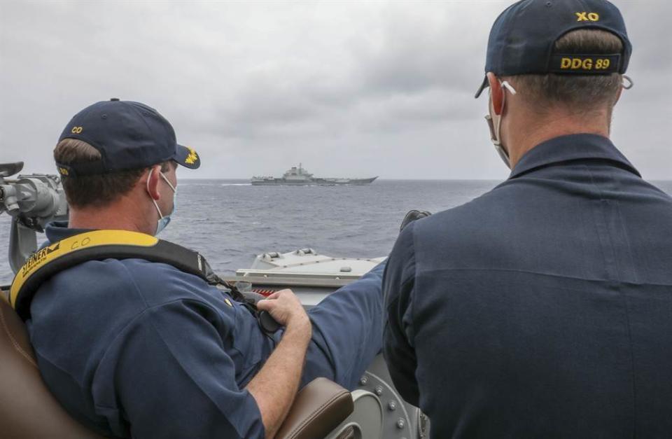 「馬斯廷」號（USS Mustin，DDG-89）驅逐艦艦長羅伯特·布里格斯（Robert J. Briggs，左）4日蹺著雙腿，和副艦長斯萊（Richard D. Slye）從艦橋操舵室外監視數千公尺外的解放軍航母「遼寧」艦。（美國海軍）