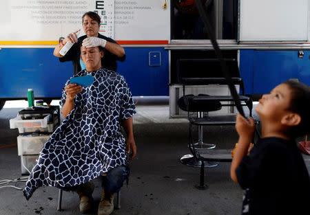 A Central American migrant, moving in a caravan through Mexico and traveling to request asylum in U.S, cuts his hair as he arrives to Mexicali, Baja California state, Mexico April 25, 2018. REUTERS/Edgard Garrido