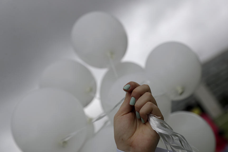 A nurse holds balloons representing lives that could be saved by COVID-19 vaccinations on World Health Day outside the national Congress in Brasilia, Brazil, Wednesday, April 7, 2021. (AP Photo/Eraldo Peres)