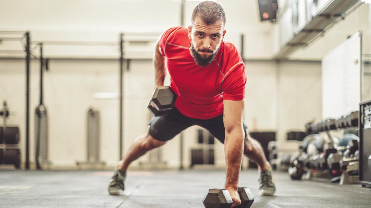  Man doing renegade row exercise with dumbbells. 