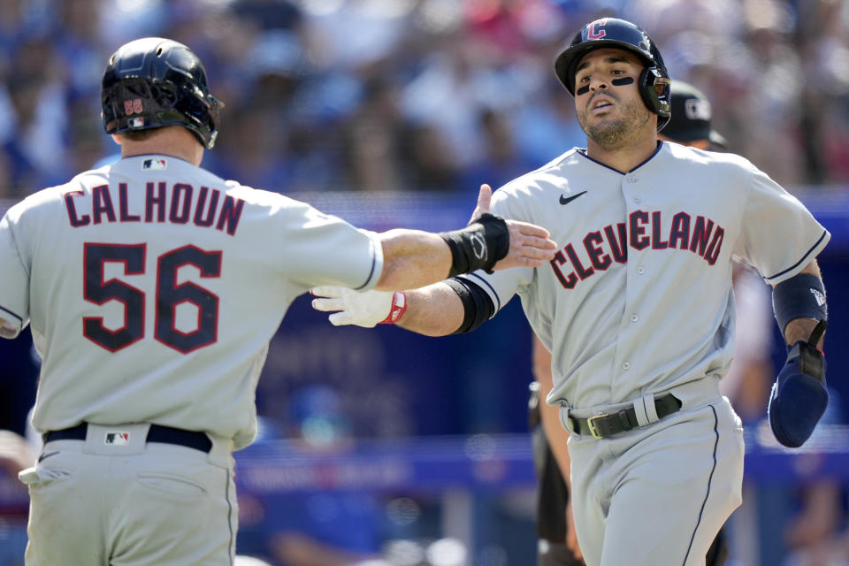 Cleveland Guardians first baseman Kole Calhoun (56) celebrates with teammate Ramon Laureano (10) after getting batted in by teammate Andres Gimenez (0) with a double during the eighth inning of a baseball game against the Toronto Blue Jays in Toronto, Sunday, Aug. 27, 2023. (Frank Gunn/The Canadian Press via AP)