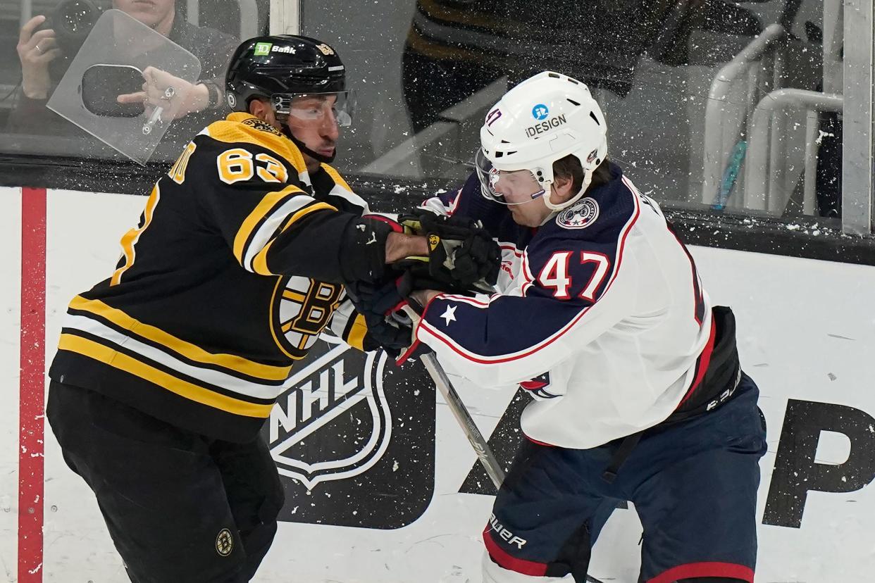 Boston Bruins left wing Brad Marchand (63) and Columbus Blue Jackets defenseman Marcus Bjork (47) grapple in the first period of an NHL hockey game, Thursday, March 30, 2023, in Boston. (AP Photo/Steven Senne)