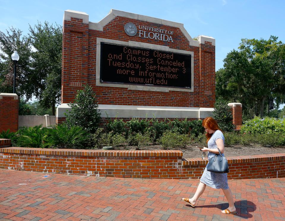 A woman walks past a University of Florida welcome sign on the UF campus off University Ave., in Gainesville, Fla. on September 5, 2019.