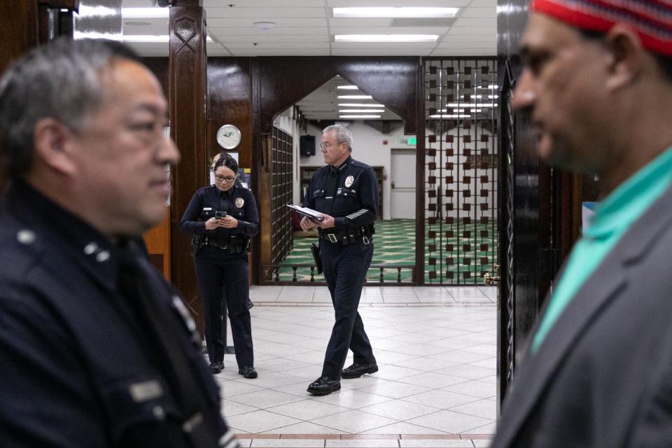 Three police officers and a man stand and talk inside a mosque.