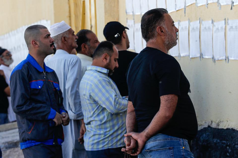 Voters look for their names on a list during parliamentary elections at a polling station in Najaf, Iraq, Sunday, Oct. 10, 2021. Iraq closed its airspace and land border crossings on Sunday as voters headed to the polls to elect a parliament that many hope will deliver much needed reforms after decades of conflict and mismanagement. (AP Photo/Anmar Khalil)
