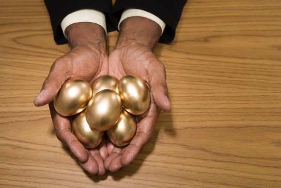 Man's hands holding six golden eggs, retirement nest egg concept
