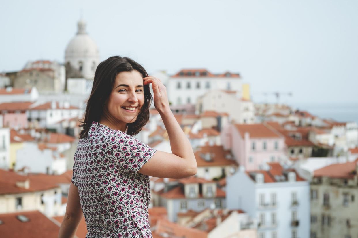 A woman posing for a photo overlooking a city.