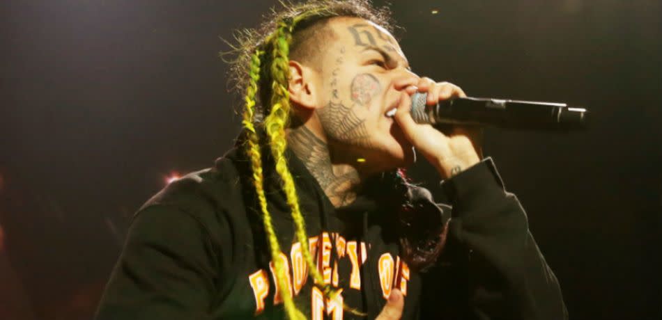 Tekashi 6ix9ine grimaces as he hollers into a microphone.