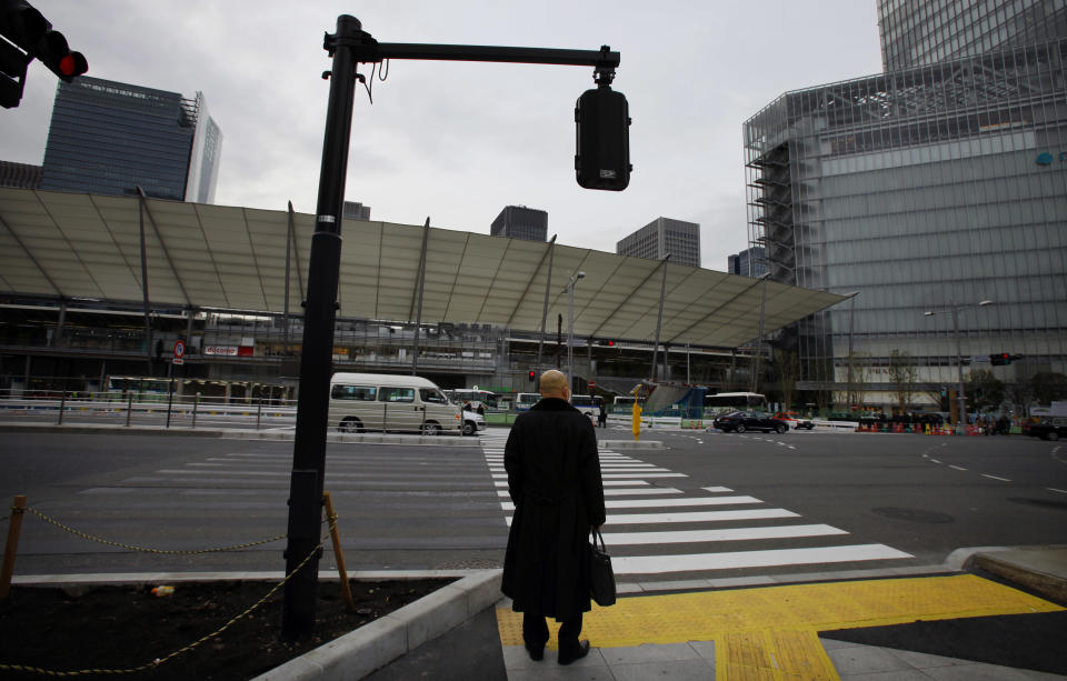 In this Thursday, Feb. 13, 2014 photo, a man waits at a crossing in a business district in Tokyo. Despite Japan’s prime minister Shinzo Abe's declaration that “Japan is back” in a speech last year to the New York Stock Exchange, Abe faces a thornier challenge in ensuring that his “Abenomics” recovery from two decades of economic stagnation spreads beyond boardrooms and investment portfolios. (AP Photo/Junji Kurokawa)