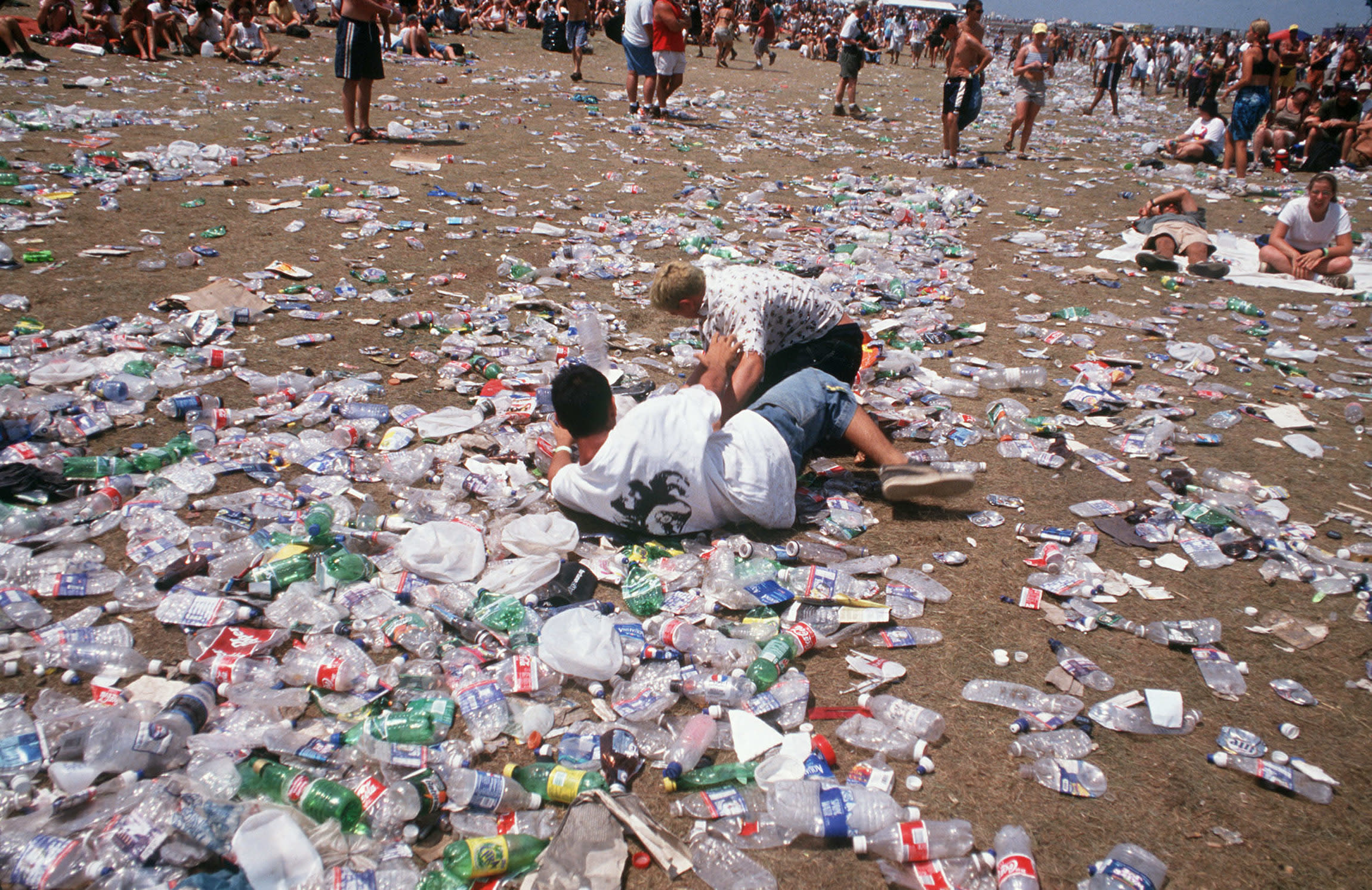 Festival-goers rest among the rubbish on the ground.