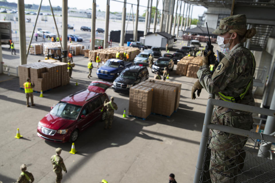 A Indiana National Guardsmen watches over the distribution of food at the Indianapolis Motor Speedway in Indianapolis, Saturday, May 23, 2020. Gleaners Food Bank of Indiana expected to distribute boxes of fresh produce, lean meat, and dairy to more than 5,000 people at the event. The Speedway hosted the event on what would have been the eve of the Indianapolis 500 that was postponed due to the coronavirus outbreak. (AP Photo/Michael Conroy)