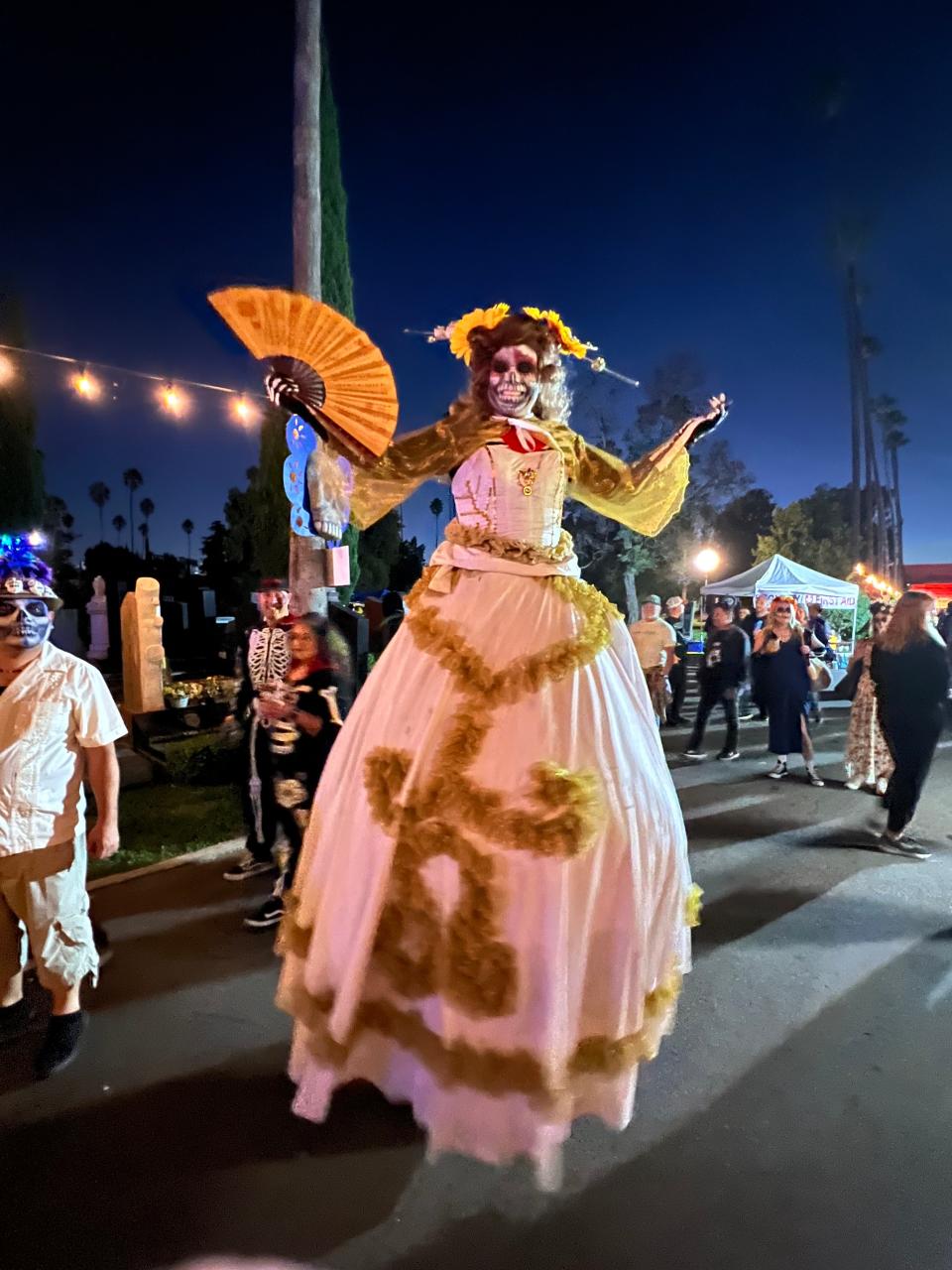 A woman dressed up and walking on stilts poses during the Día de Los Muertos celebration at the Hollywood Forever Cemetery in Los Angeles on Saturday, Oct. 28, 2023.