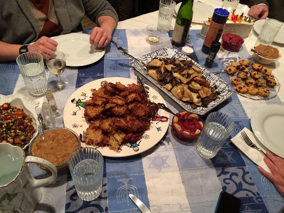 Latkes – fried potato pancakes – are one of the most popular Hanukkah foods in the U.S., usually served with applesauce or sour cream. <a href="https://www.gettyimages.com/detail/news-photo/having-a-meal-at-private-hannukah-party-on-6th-night-12-31-news-photo/530882869?adppopup=true" rel="nofollow noopener" target="_blank" data-ylk="slk:Lisa J Goodman/Moment Mobile via Getty Images;elm:context_link;itc:0;sec:content-canvas" class="link ">Lisa J Goodman/Moment Mobile via Getty Images</a>