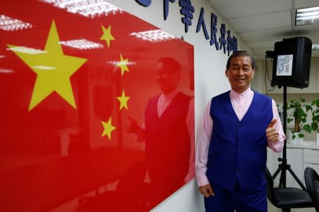 Chang An-lo, known as "White wolf", leader of the Chinese Unification Promotion Party (CUPP), poses next to a China national flag after an interview in Taipei