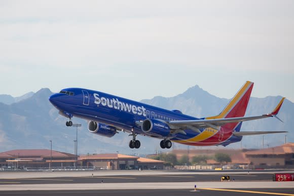 A Southwest Airlines plane taking off, with mountains in the background.