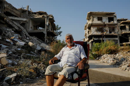 Kamal Shtewi, a resident of al-Khalidiya neighbourhood, poses for a photograph in front of destroyed buildings in al-Khalidiya area, in the government-controlled part of Homs, Syria, September 18, 2018. REUTERS/Marko Djurica