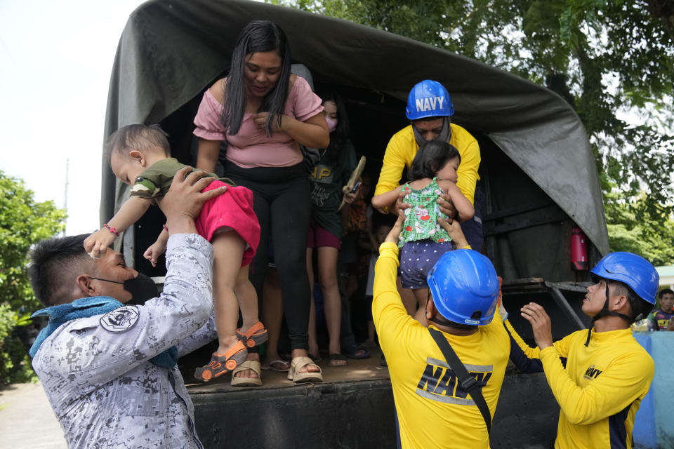 Philippine Navy personnel help bring down children from a military truck as they arrive at an evacuation center in Santo Domingo town, Albay province, northeastern Philippines, Tuesday, June 13, 2023. Truckloads of villagers on Tuesday fled from Philippine communities close to gently erupting Mayon volcano, traumatized by the sight of red-hot lava flowing down its crater and sporadic blasts of ash. (AP Photo/Aaron Favila)