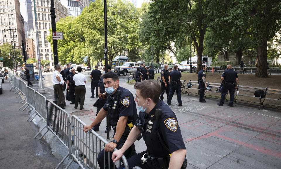 Police stand behind barricades at a park adjacent to City Hall, Wednesday, July 22, 2020, in New York. Police in riot gear cleared a month-long encampment of protesters and homeless people from the park earlier in the morning. (AP Photo/Mark Lennihan)