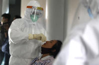 A heath worker takes a nasal swab sample during a public testing for the coronavirus conducted at a market in Bali, Indonesia on Saturday, June 6, 2020. (AP Photo/Firdia Lisnawati)