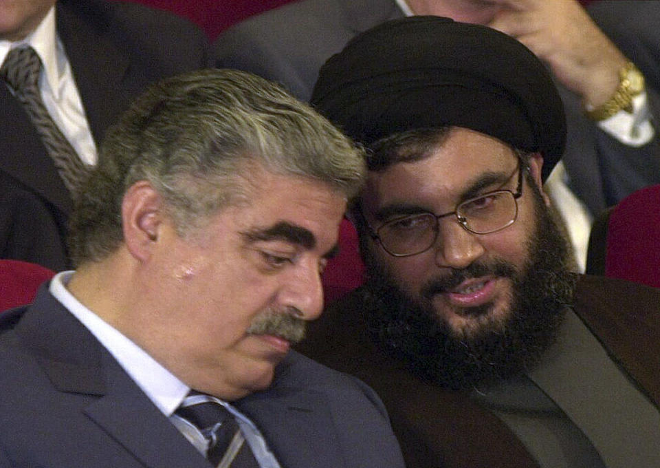 FILE - Former Lebanese Prime Minister Rafik Hariri, left, talks with Hezbollah leader Sheik Hassan Nasrallah, right, during an official ceremony to mark the first anniversary of the Israeli withdrawal from south Lebanon, in Beirut, Lebanon, May 25, 2001. Forty years since it was founded, Lebanon's Hezbollah has transformed from a ragtag organization to the largest and most heavily armed militant group in the Middle East. (AP Photo/Mahmoud Tawil, File)